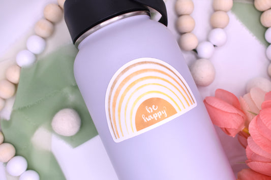 Yellow gradient rainbow sticker with white background and the words "be happy" - sticker displayed on grey waterbottle